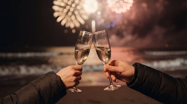 Two people toasting champagne on the beach with fireworks celebrating a New Year mental health reset in Lake Worth Florida